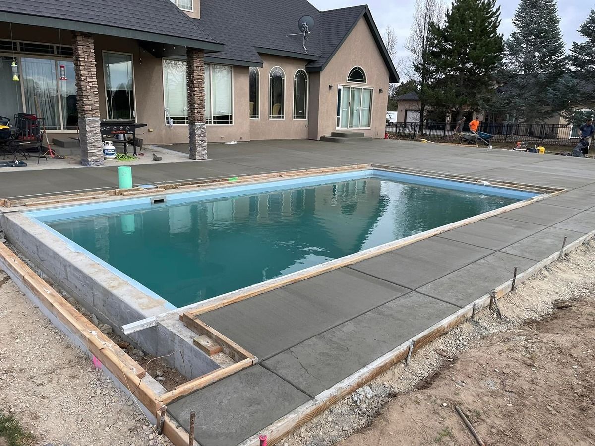 Backyard swimming pool under construction beside a modern house, with unfinished deck and patio area