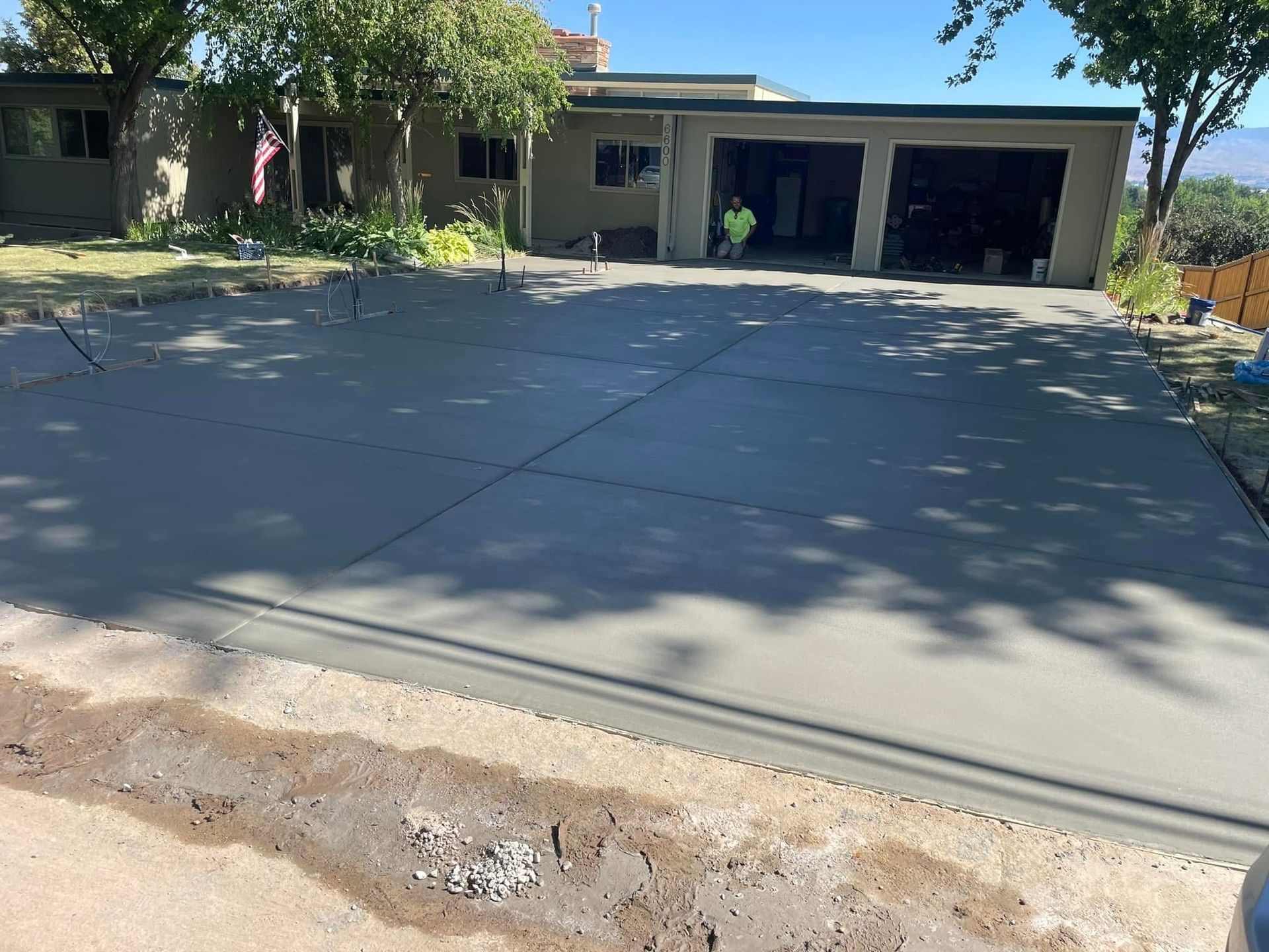 Residential driveway and house with a two-car garage in bright sunlight.