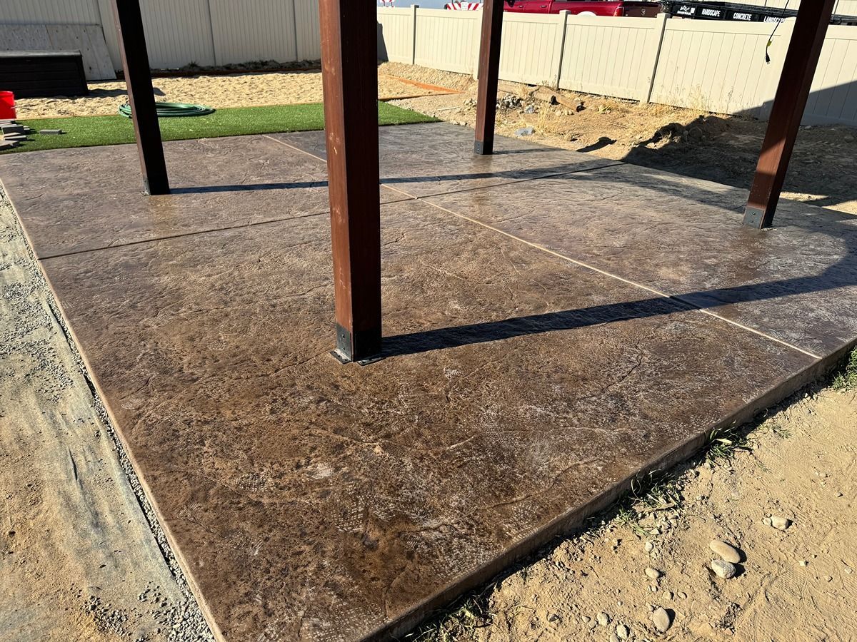 Concrete slab foundation with rust-colored metal posts in a fenced yard area