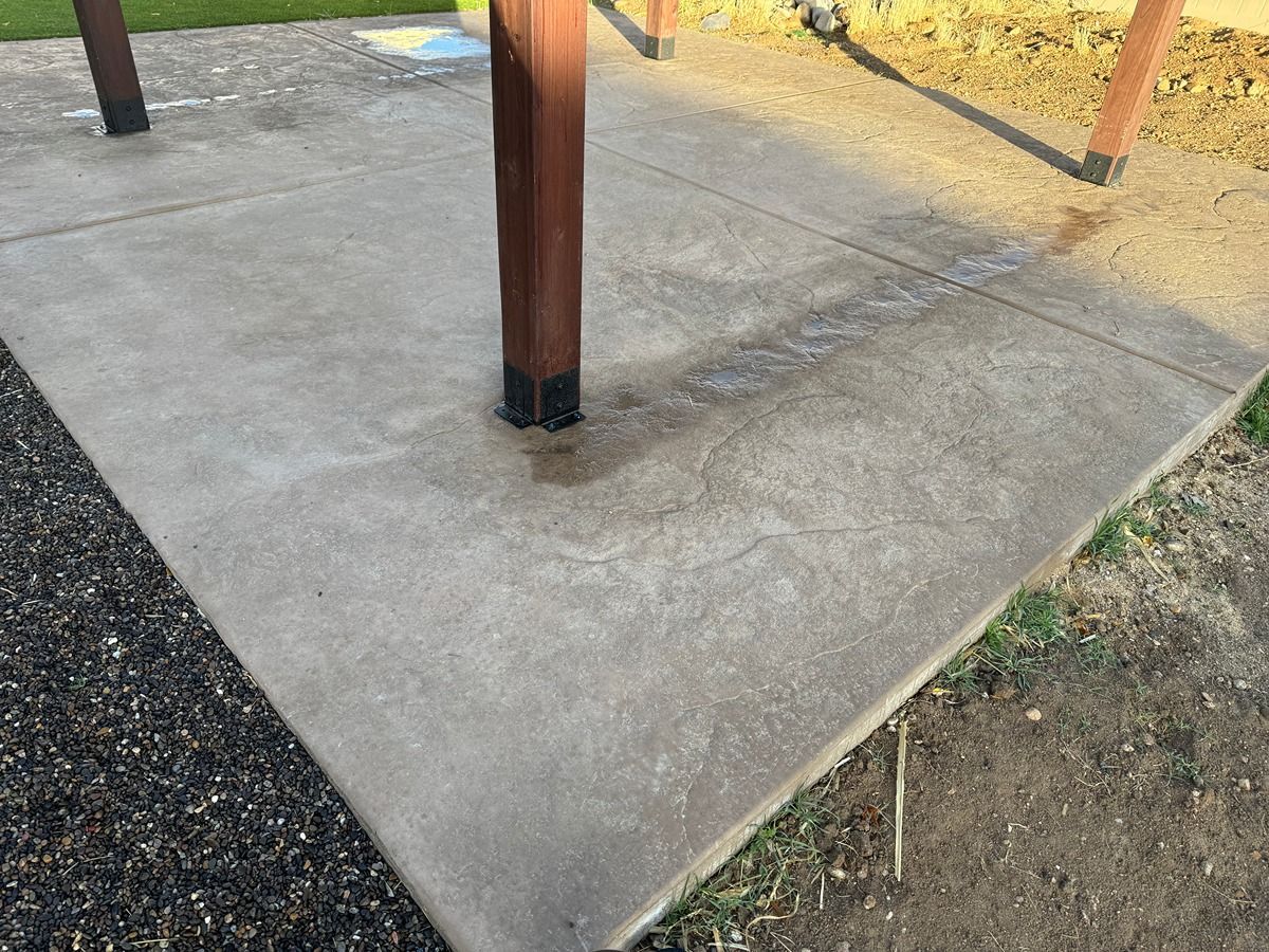 Concrete patio slab with a wooden post and gravel border outdoors