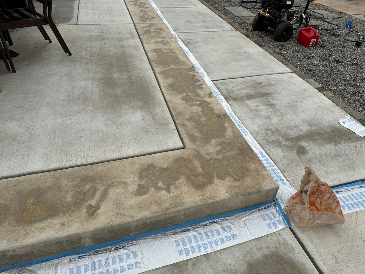 Fresh concrete driveway edge with blue forms, gravel, and a small caution cone near the corner.