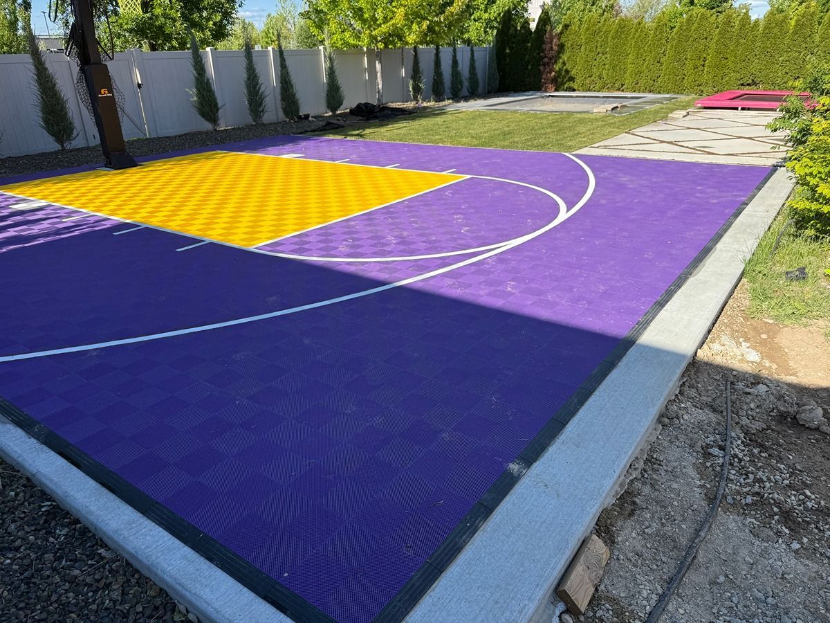 Colorful outdoor basketball court with purple surface, yellow key, and white lines in a fenced yard