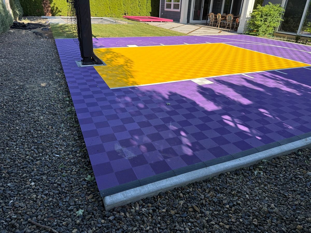 Outdoor patio with purple checkered flooring, a yellow section, and gravel along the edge near a building