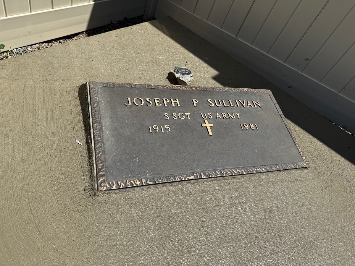 Gravestone plaque for Joseph T. Sullivan, with gold lettering and a cross on a concrete surface.