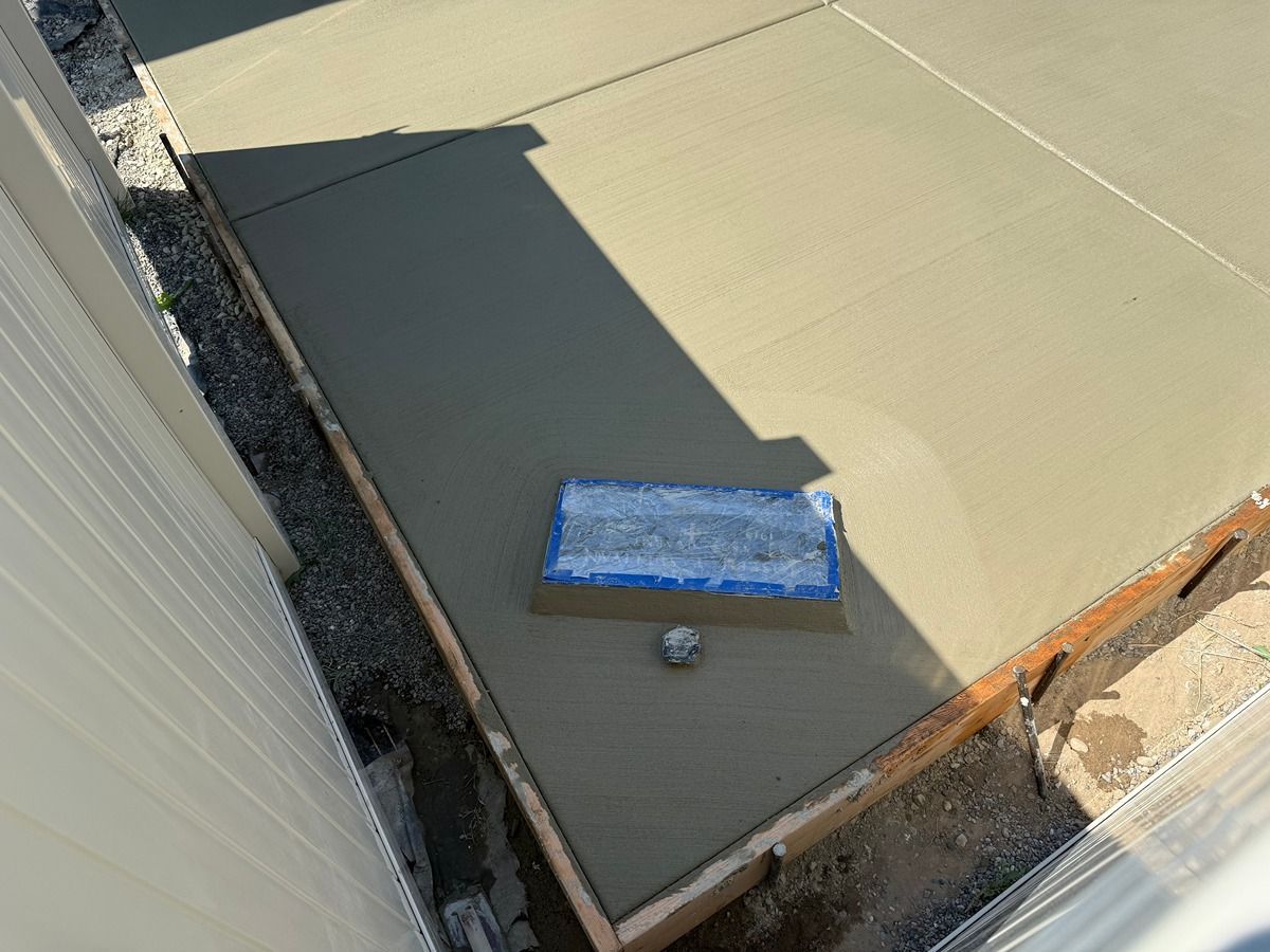 Flat rooftop corner with gray surface, a blue vent or skylight, and a circular roof fixture near the edge.