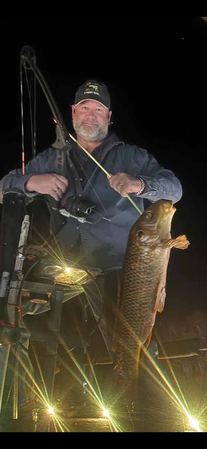 A man is sitting on a boat holding a large fish.