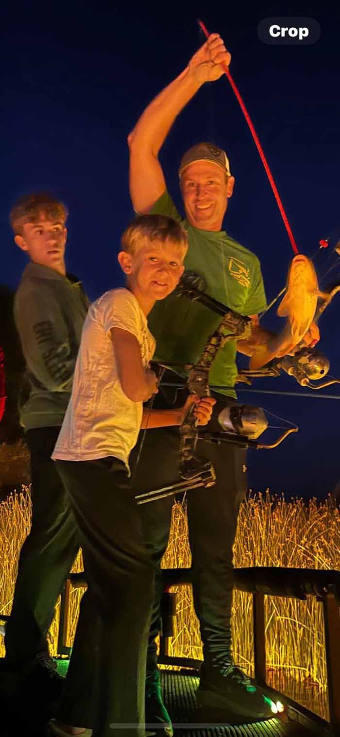 A man and two children are standing next to each other holding bows and arrows.