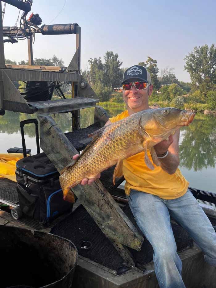 A man is sitting on a boat holding a large fish.