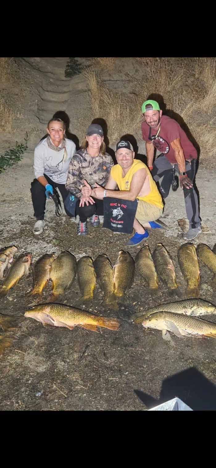 A group of people standing next to a pile of fish.