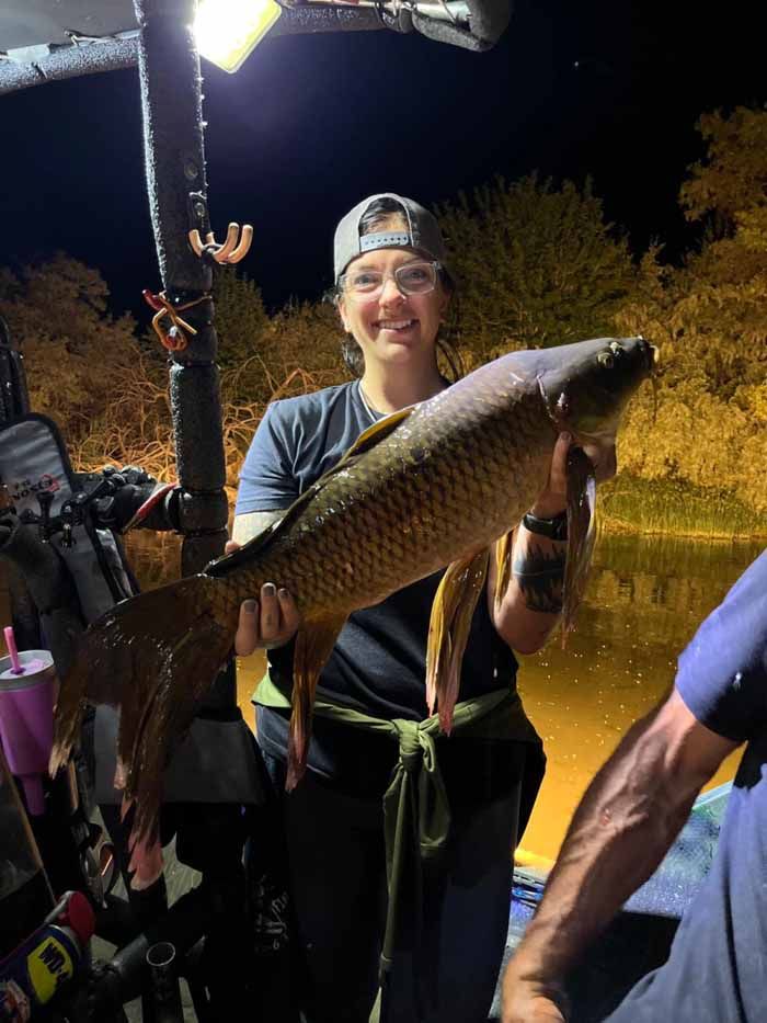 A woman is holding a large fish in her hands.