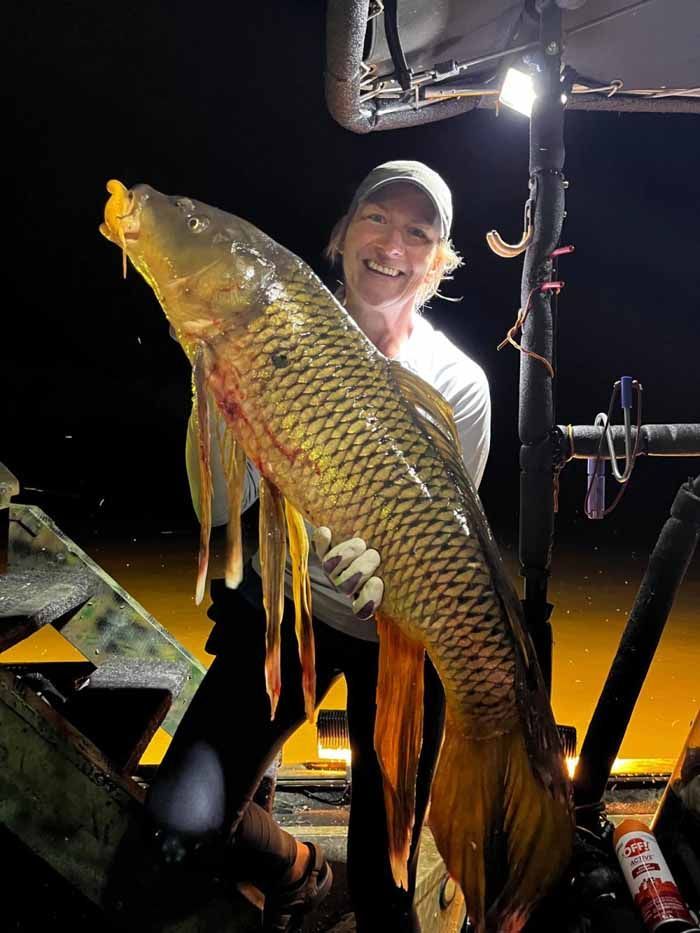 A man is holding a large fish in his hands.
