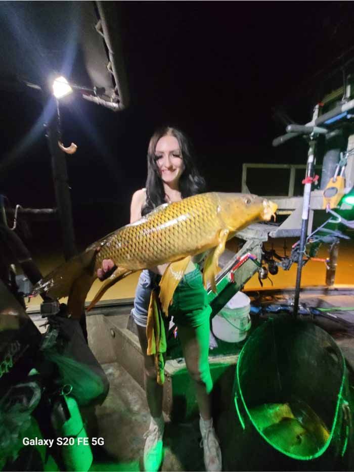A woman is holding a large fish in her hands.