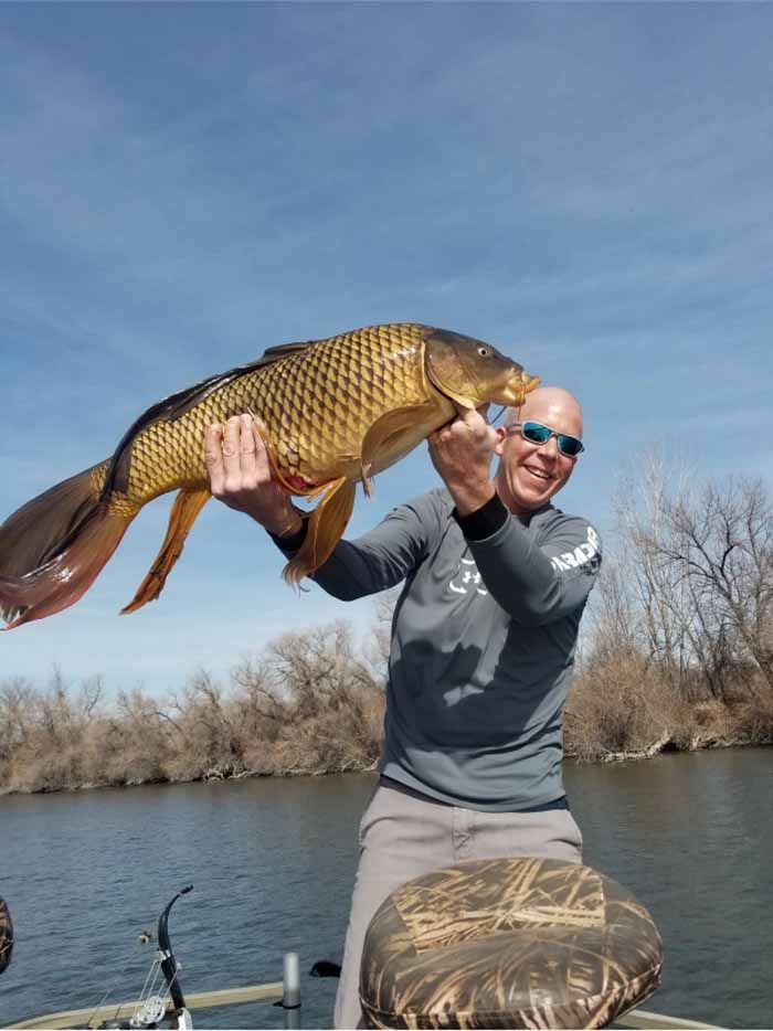 A man on a boat is holding a large fish in his hands.