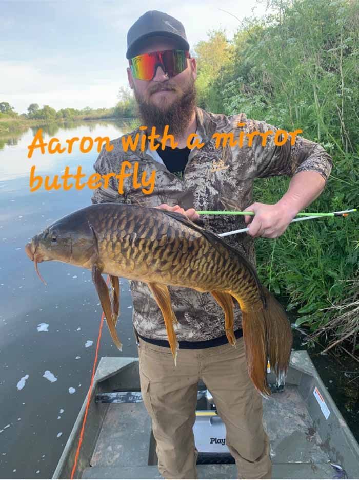 A man is standing on a boat holding a large fish.