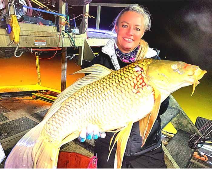 A woman is holding a large fish in her hands.