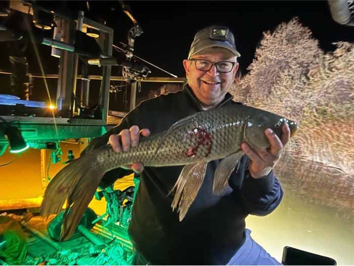 A man is holding a large fish in his hands