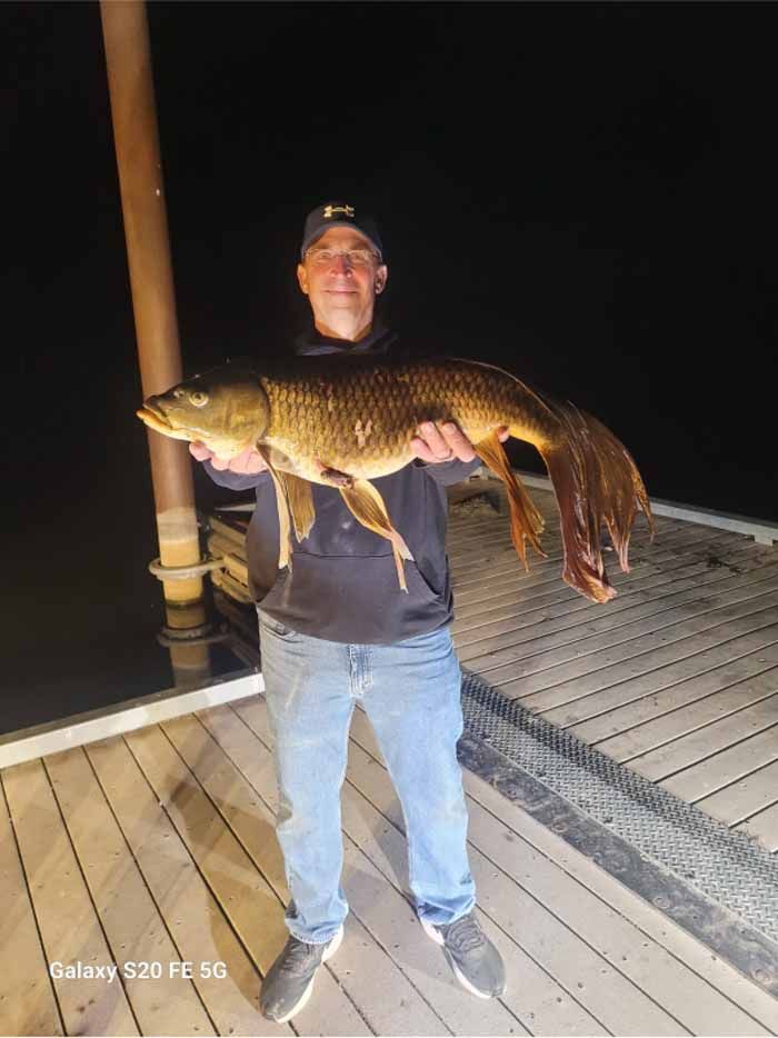 A man is holding a large fish on a dock.