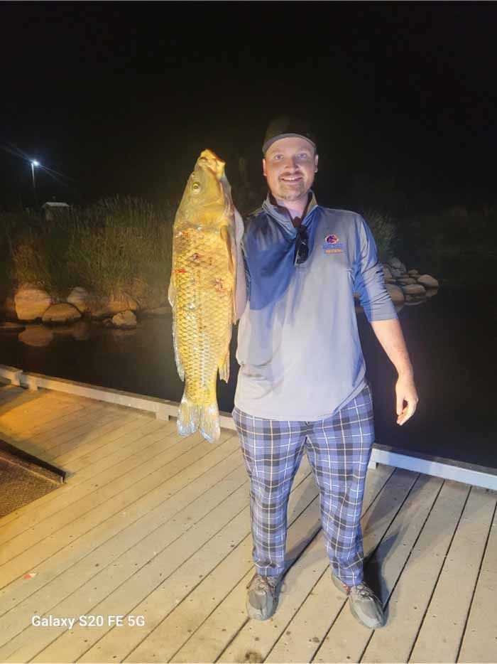 A man is standing on a dock holding a large fish.