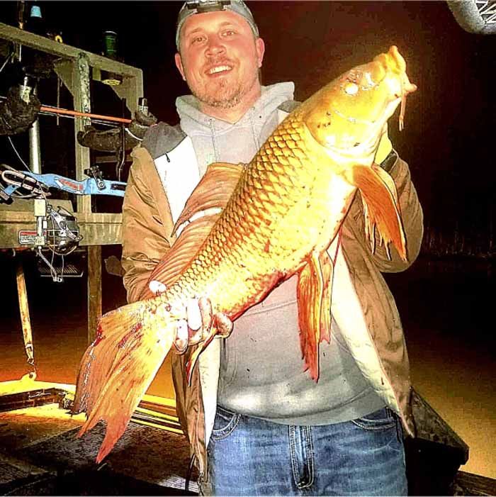 A man is holding a large fish in his hands