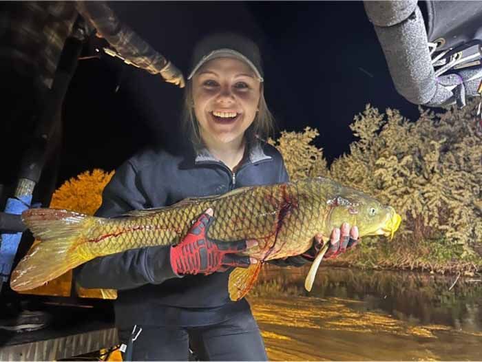 A woman is holding a large fish in her hands.