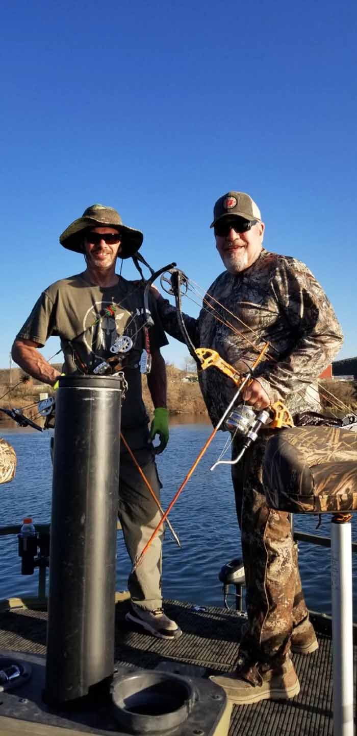 Two men are standing on a boat holding fishing rods.