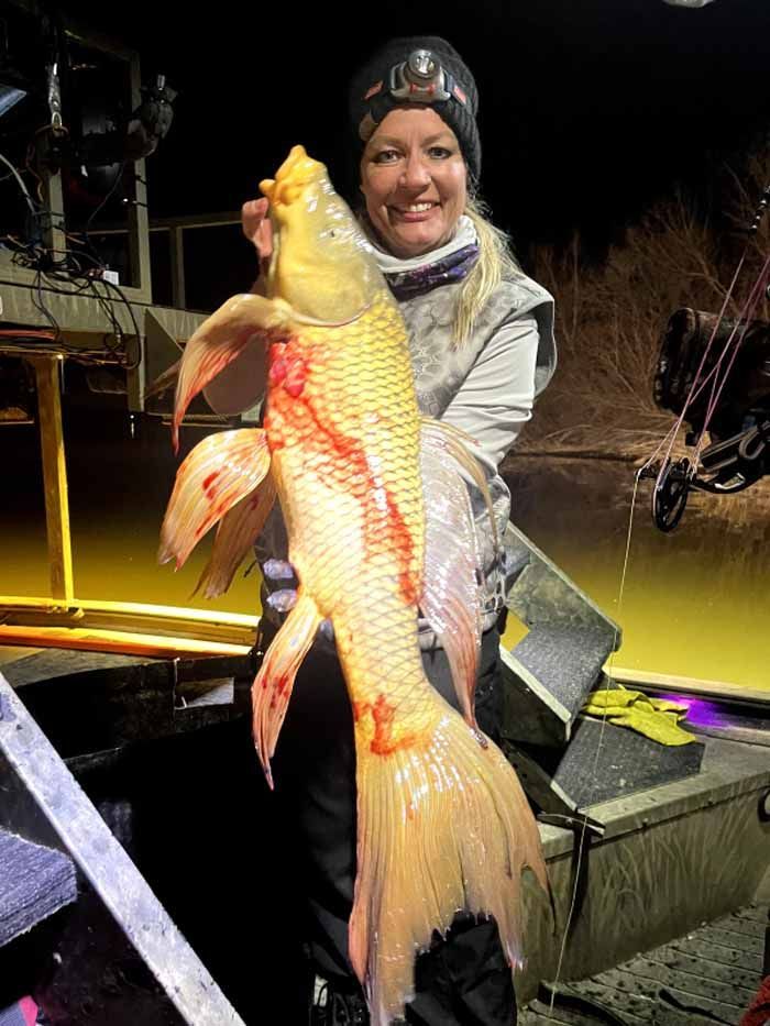 A woman is holding a large fish in her hands.