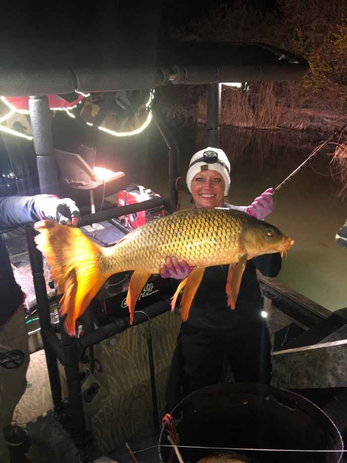 A woman is holding a large fish in her hands.