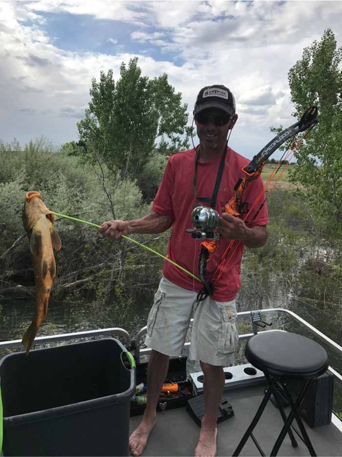 A man is standing on a boat holding a fishing rod and a fish.