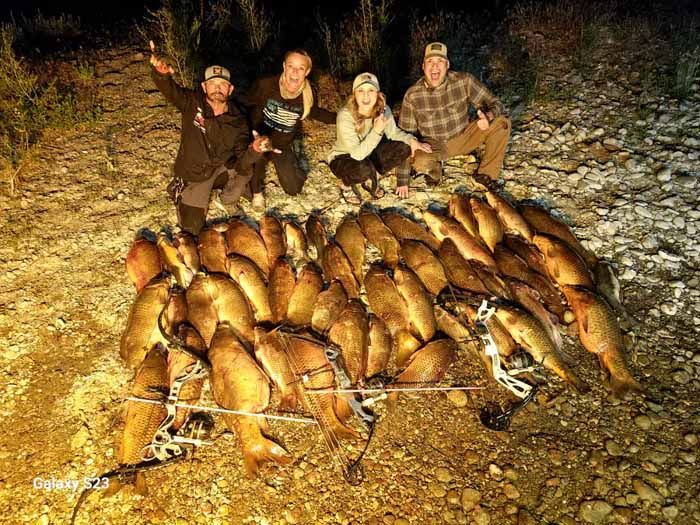 A group of people are standing around a pile of fish.