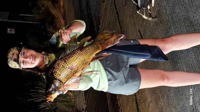 A woman is holding a large fish in her hands.