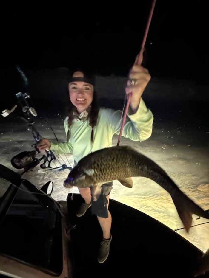 A woman is holding a large fish on a fishing rod.