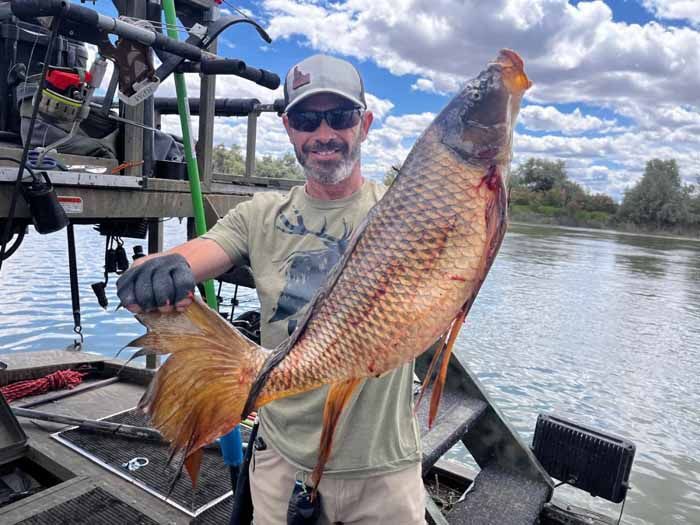 A man is holding a large fish in his hands on a boat.