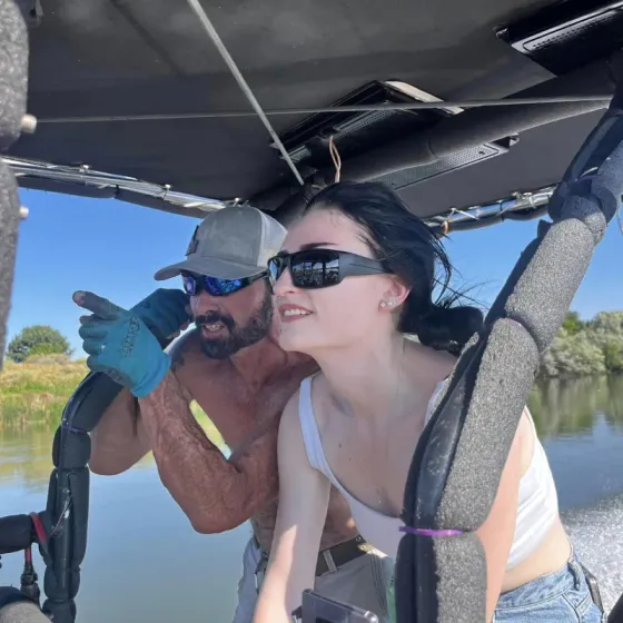 A man and a woman are sitting in a vehicle near a body of water.