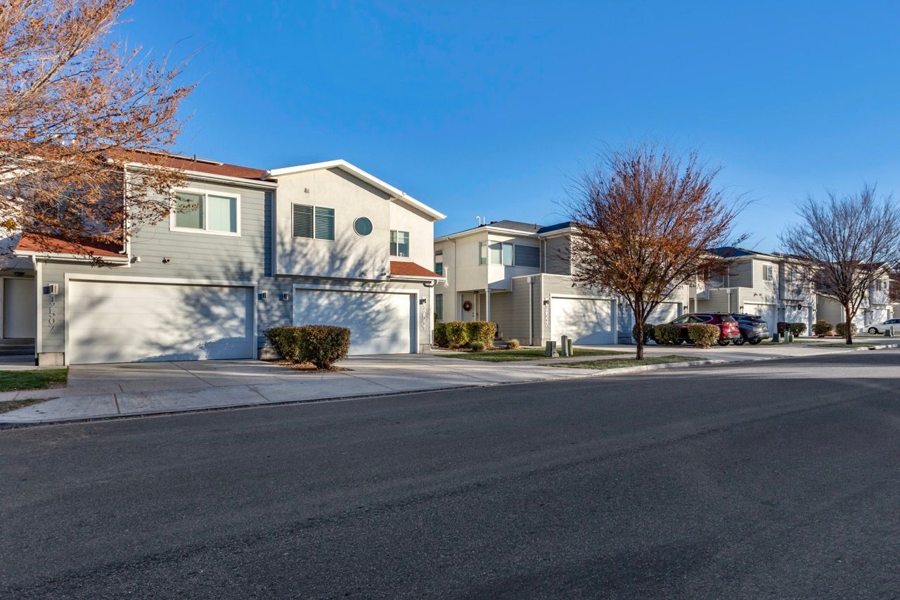 Row of modern townhomes with attached garages along a quiet residential street.