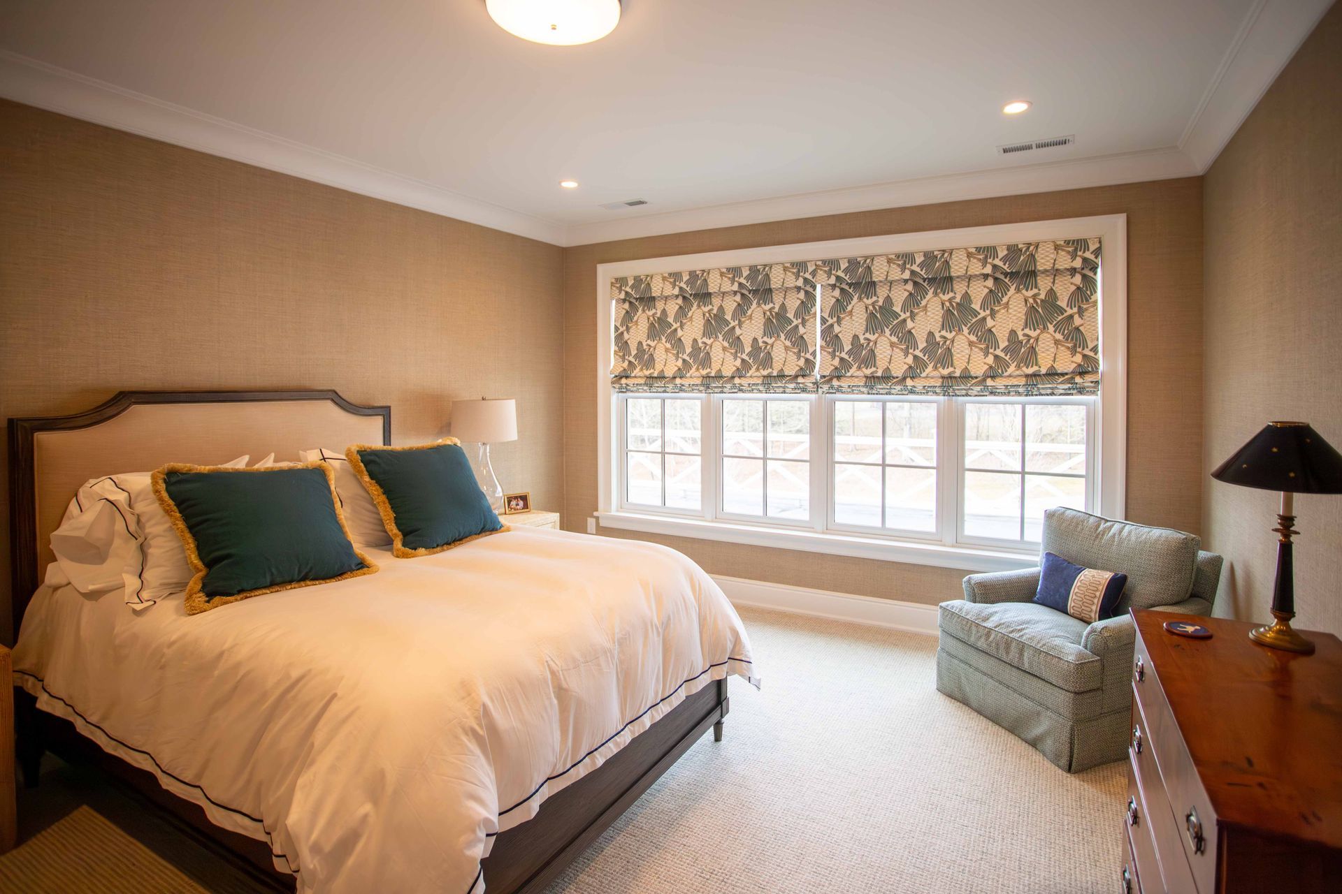 Cozy bedroom with a large bed, window seat, and beige decor with teal pillows