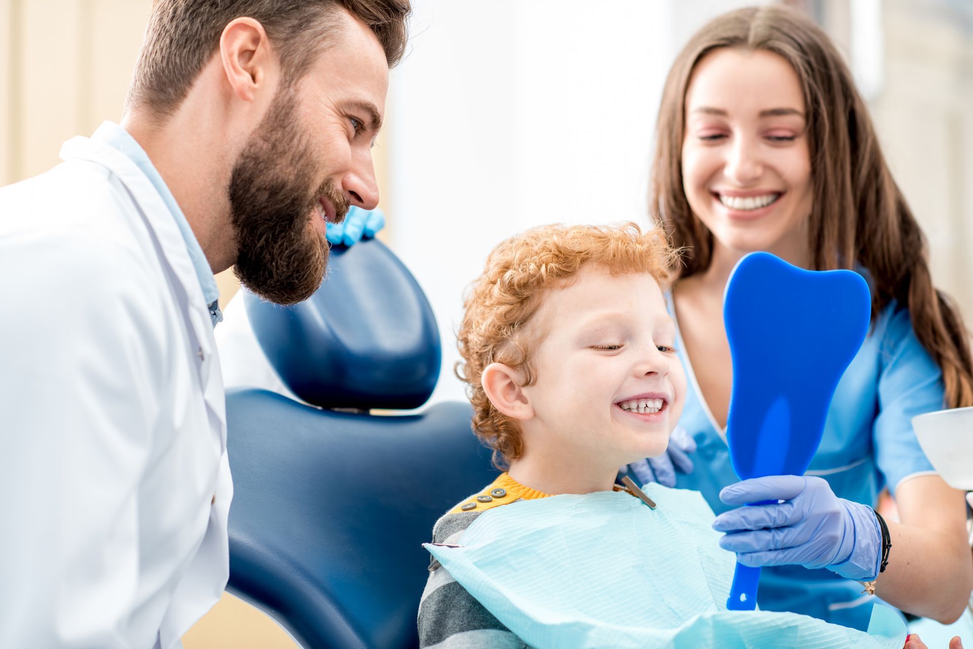 boy sitting in a dental chair with a dental professional.
