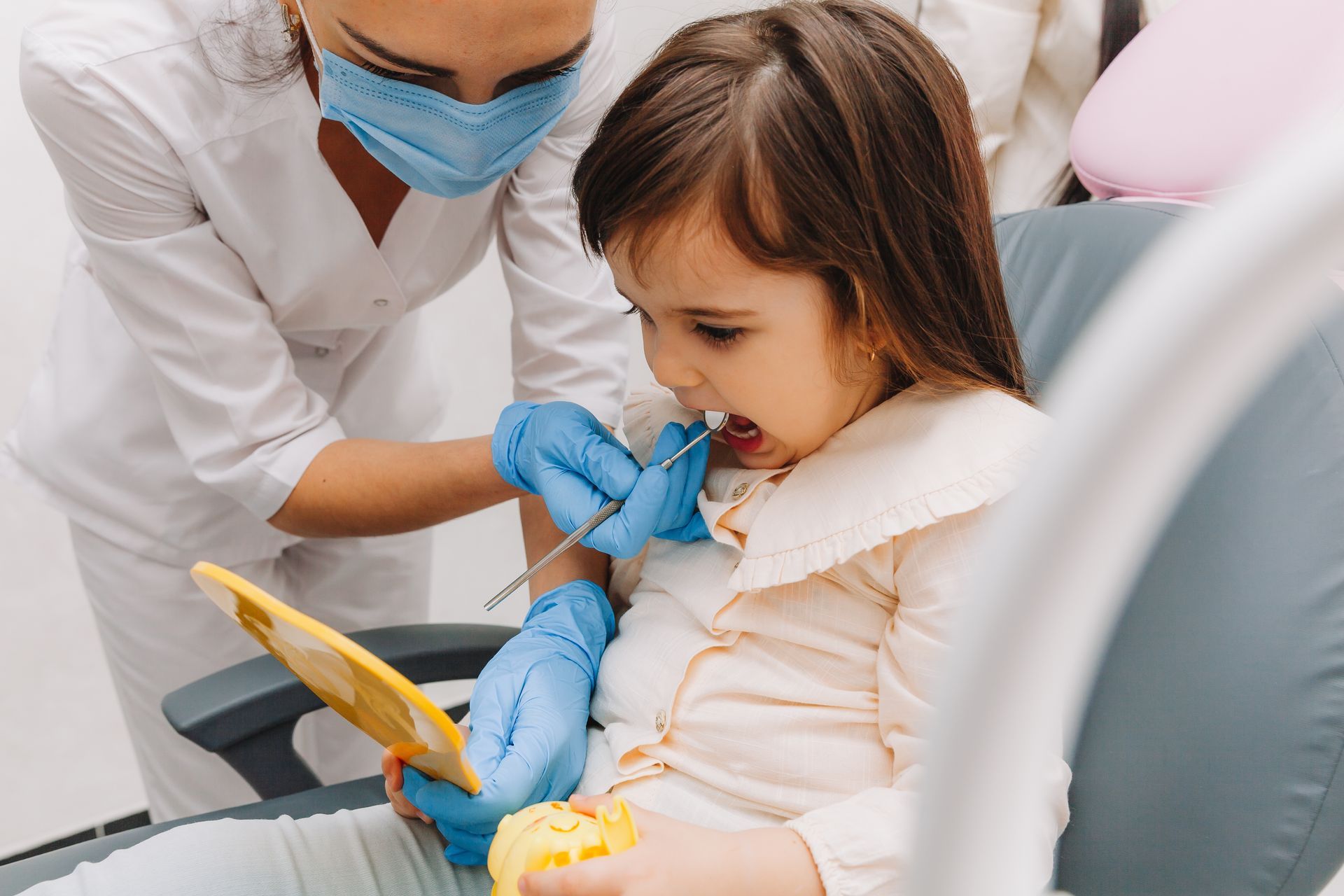A child is seeing her teeth in a mirror. A child is seeing her teeth in a mirror.