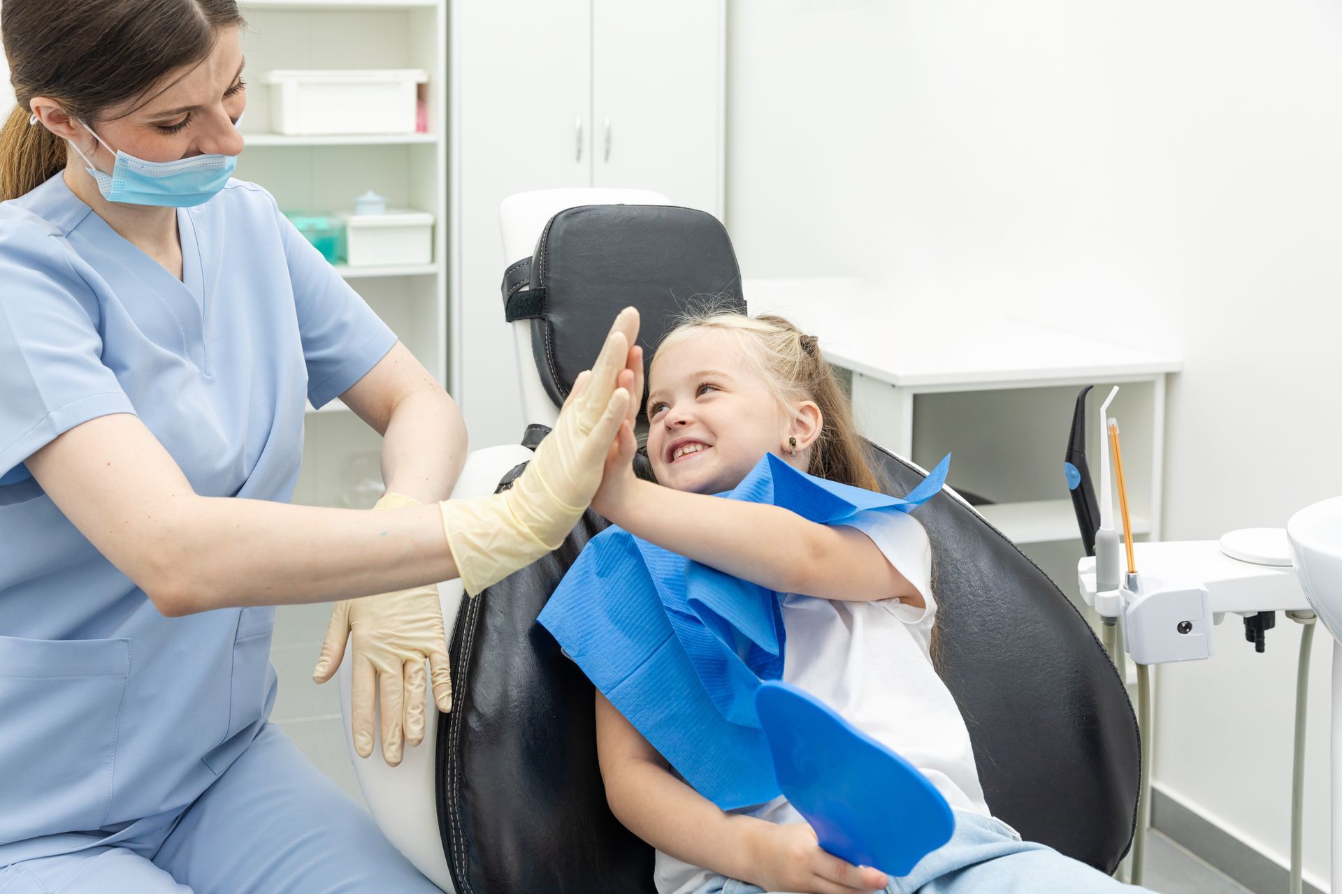 A child is giving a high-five to a dentist.