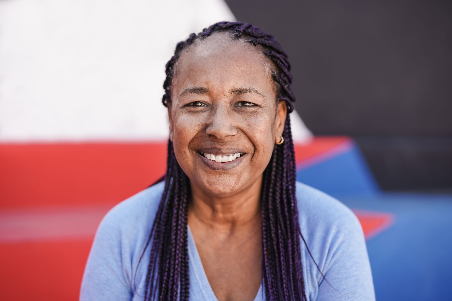 A woman with purple braids is smiling for the camera.