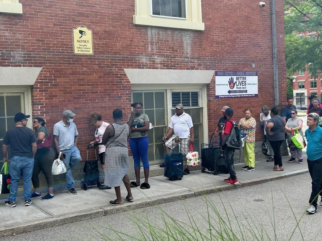 A group of people are standing outside of a brick building.