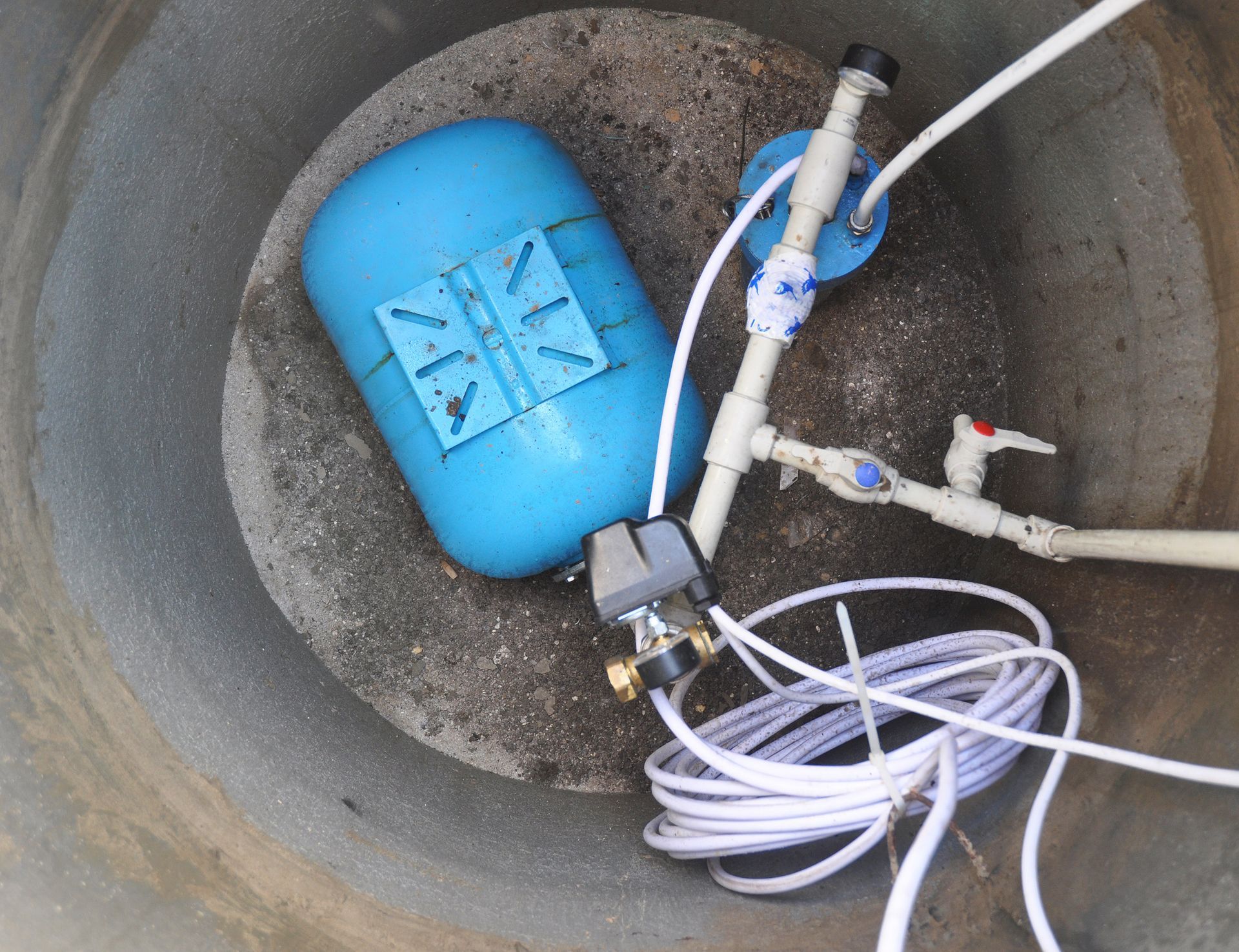 Pressure tank and piping installed inside a residential water well pit. Pressure tank and piping installed inside a residential water well pit.