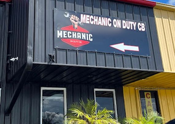 Mechanic shop sign on a black building with a red logo and white arrow pointing right | Mechanic On Duty CB LLC