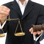Lawyer holding scales of justice and a gavel, wearing a black suit and white shirt