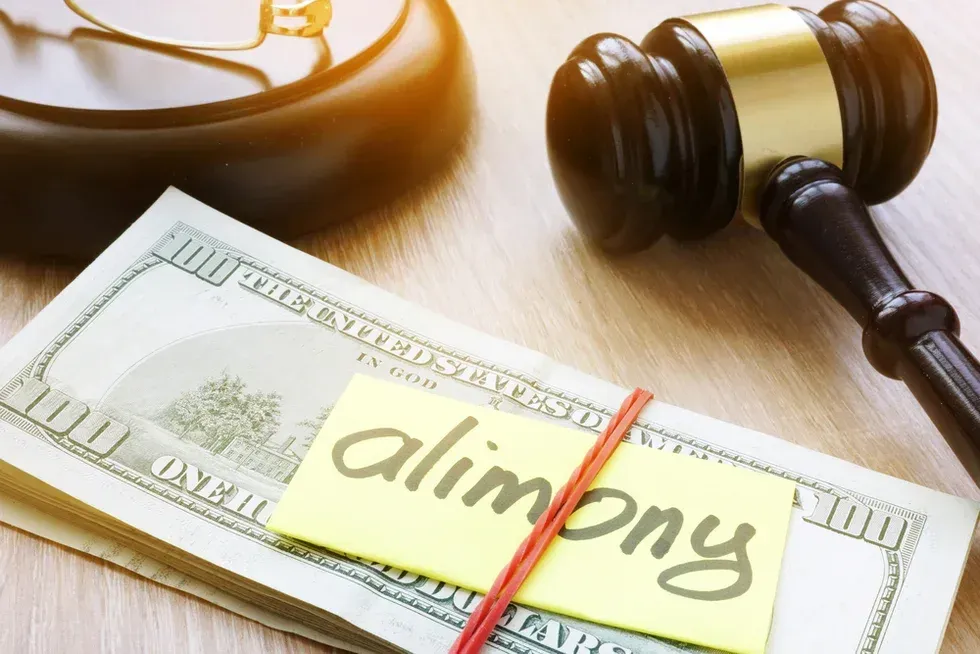 Court gavel beside dollar bills and a note labeled “alimony”