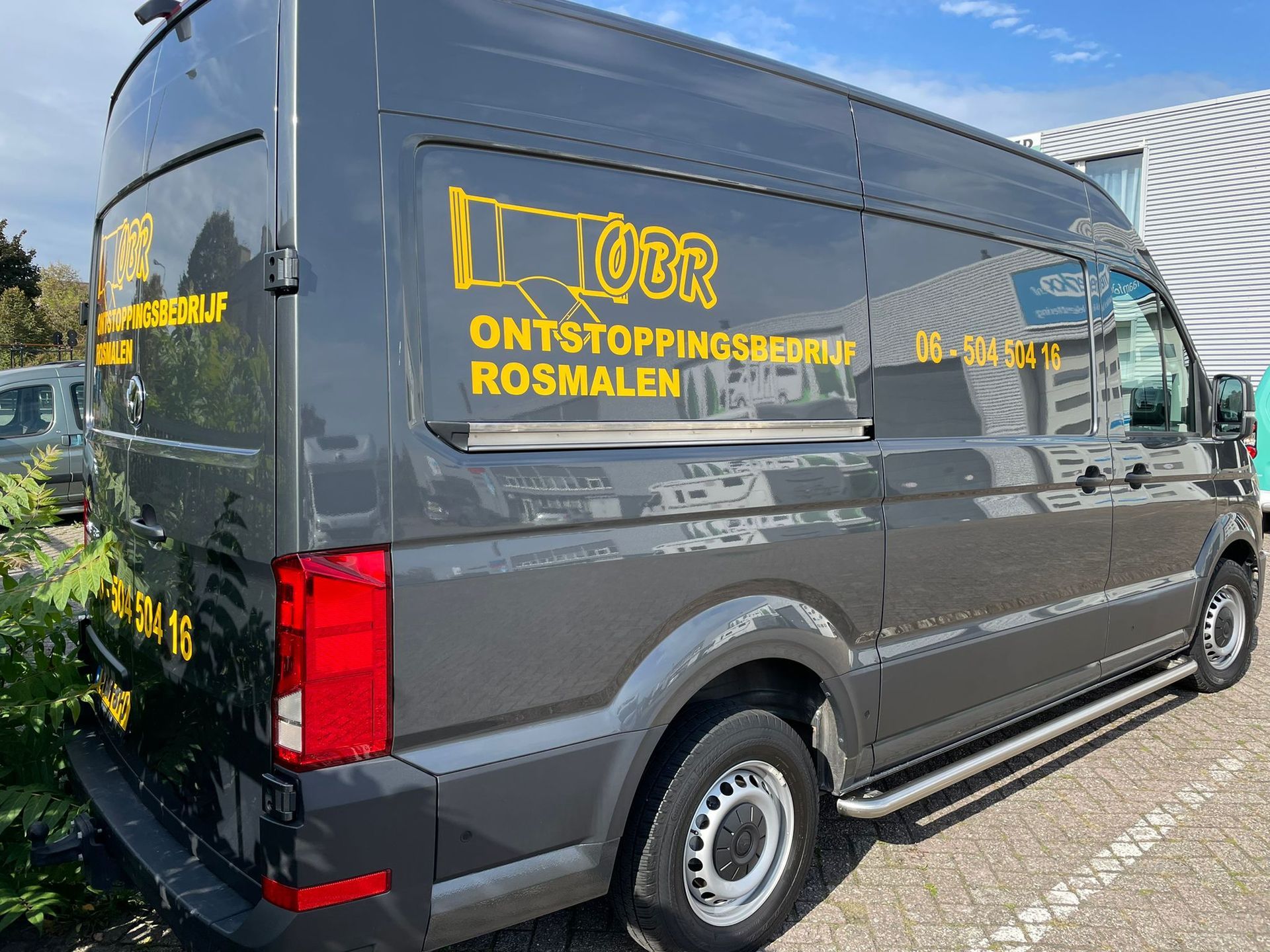 A dark gray commercial van parked outdoors with yellow