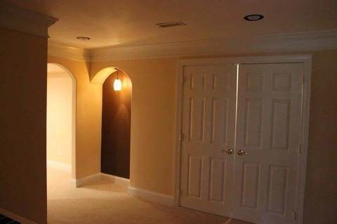 Dim hallway with arched doorways, warm lighting, and closed white double closet doors.
