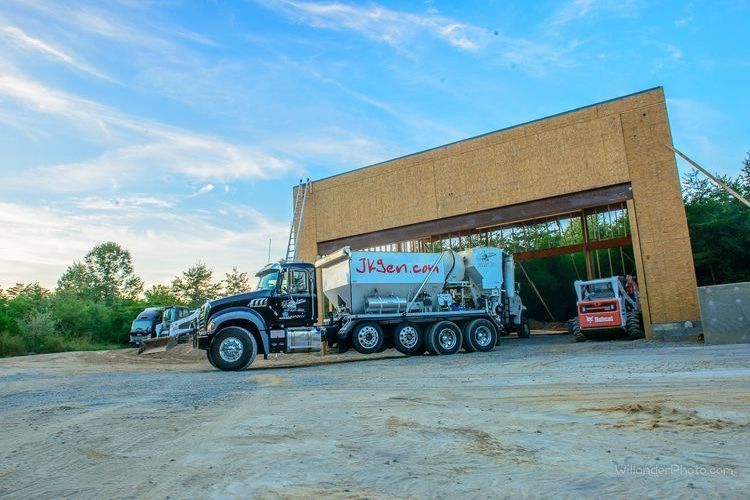 Garbage truck parked outside a large warehouse under a blue sky