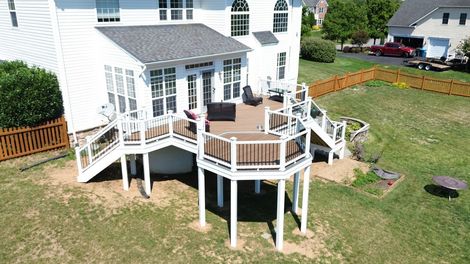 Wooden back deck with patio table, patterned rug, and suburban homes beyond the railing