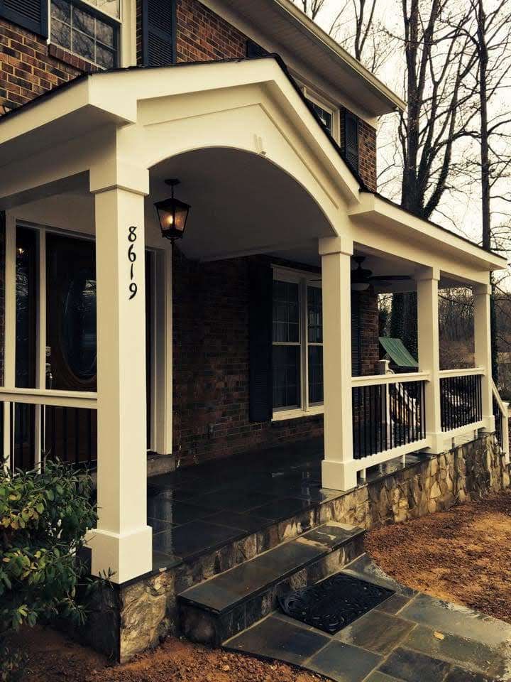 Front porch with white columns, brick walls, and black railings on a house numbered 8619