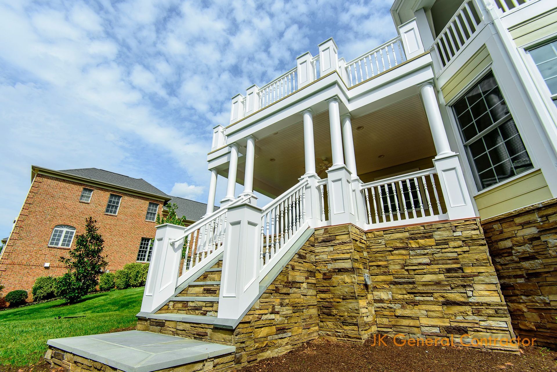 House exterior with stone walkway, light blue siding, brick columns, and ivy-covered porch under overcast sky